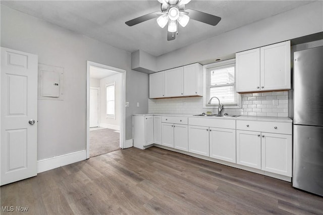 kitchen with ceiling fan, light countertops, freestanding refrigerator, wood finished floors, and a sink