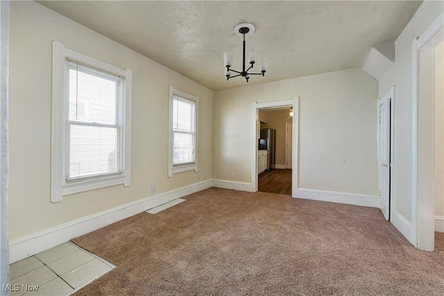 unfurnished dining area with a textured ceiling, baseboards, carpet floors, and a chandelier