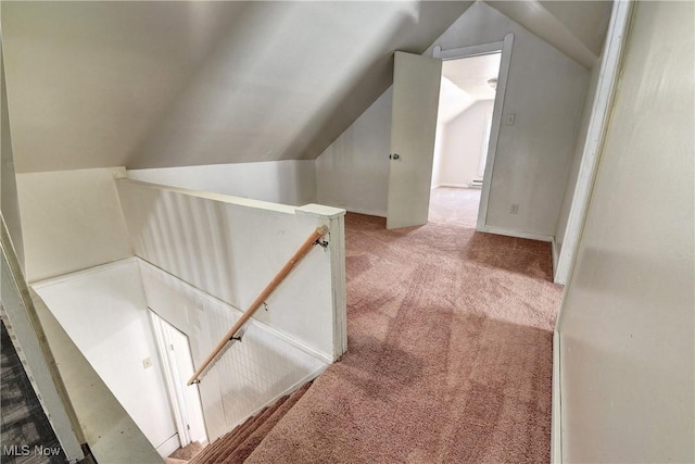 corridor with an upstairs landing, carpet floors, and vaulted ceiling