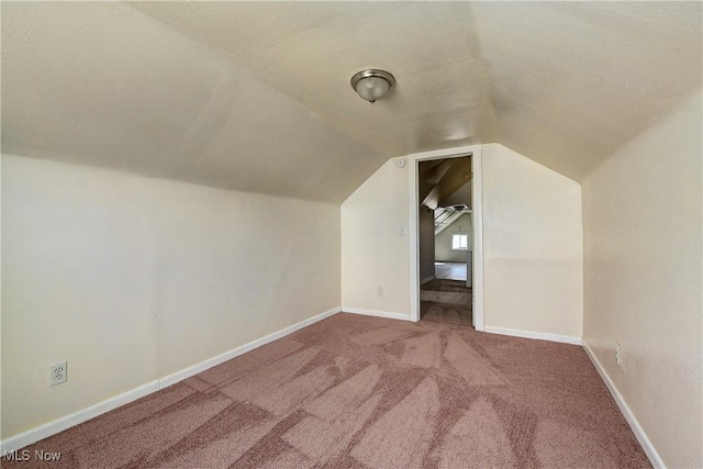 additional living space with carpet flooring, a textured ceiling, baseboards, and lofted ceiling