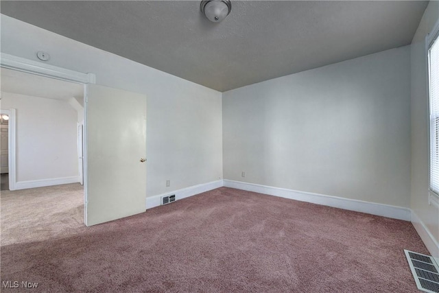 carpeted spare room with visible vents and baseboards