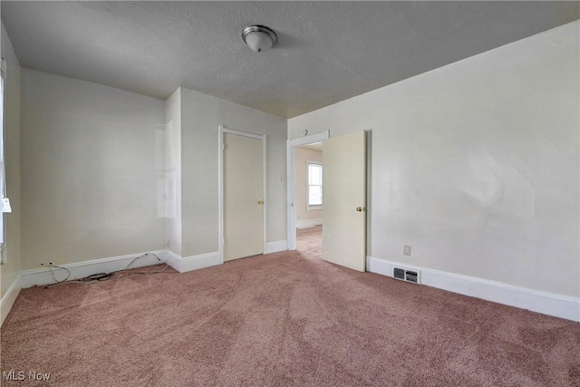 carpeted empty room with visible vents, a textured ceiling, and baseboards