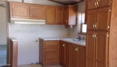 kitchen featuring brown cabinetry, light countertops, and a sink