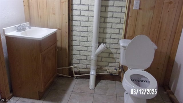 bathroom featuring tile patterned flooring, wood walls, toilet, and vanity