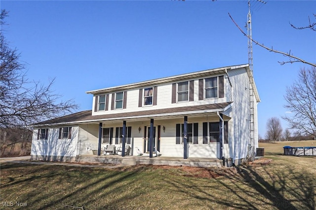 view of front of house featuring a front lawn, central air condition unit, and covered porch