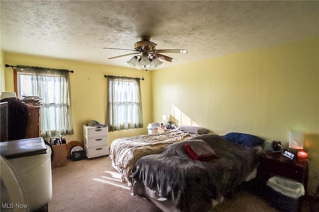 carpeted bedroom featuring multiple windows, a ceiling fan, and a textured ceiling