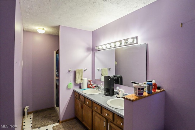 bathroom with a sink, double vanity, baseboards, and a textured ceiling