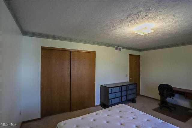 carpeted bedroom with a closet, visible vents, and a textured ceiling