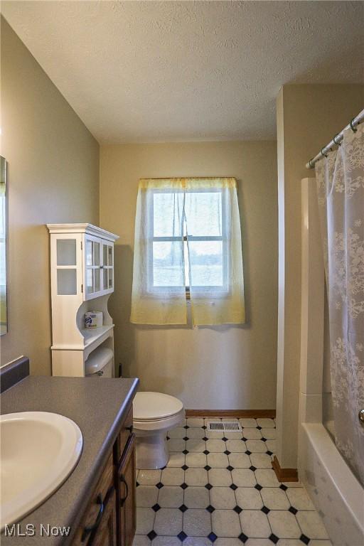 bathroom featuring visible vents, baseboards, toilet, vanity, and a textured ceiling