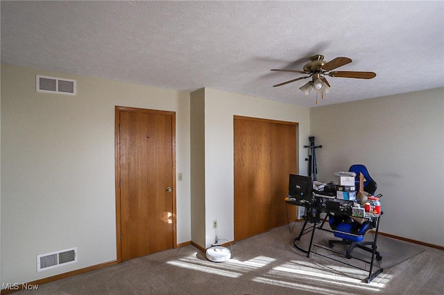 home office featuring baseboards, a ceiling fan, visible vents, and a textured ceiling