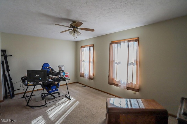 office area featuring a textured ceiling, light colored carpet, baseboards, and ceiling fan