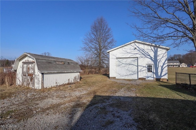 view of outbuilding featuring a garage, an outdoor structure, driveway, and fence