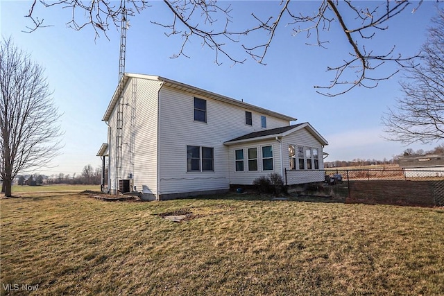 back of property featuring central air condition unit, fence, and a lawn