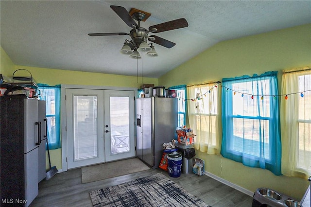 interior space with a ceiling fan, a textured ceiling, wood finished floors, french doors, and lofted ceiling