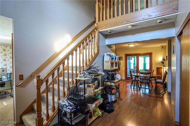 stairway featuring baseboards, a high ceiling, and wood finished floors