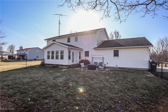 rear view of house with a fire pit, a lawn, entry steps, and fence