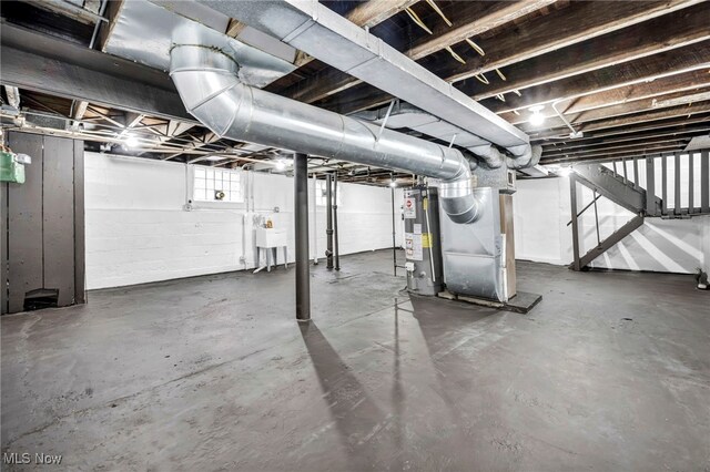 below grade area featuring heating unit, gas water heater, stairs, and a sink