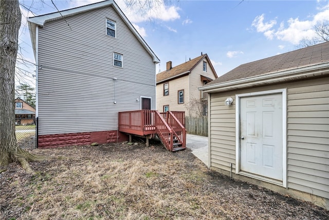 back of property featuring a deck and fence