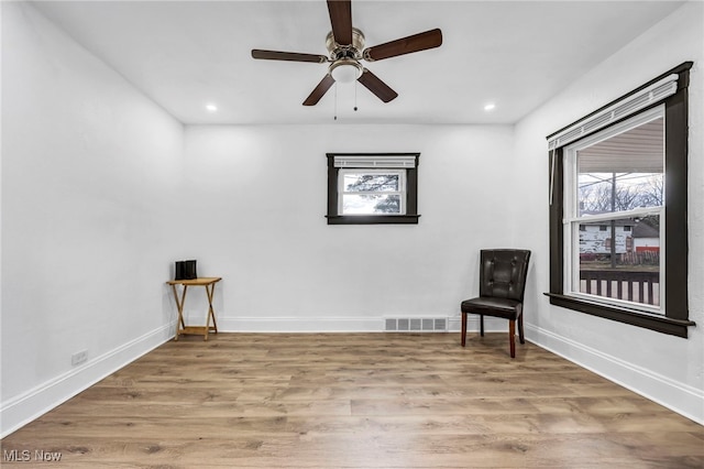 unfurnished room featuring a ceiling fan, wood finished floors, visible vents, and baseboards