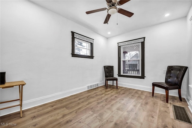 sitting room featuring ceiling fan, visible vents, baseboards, and light wood-style flooring