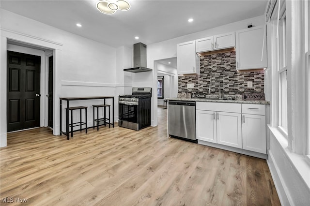 kitchen featuring white cabinetry, stainless steel appliances, wall chimney exhaust hood, and a sink