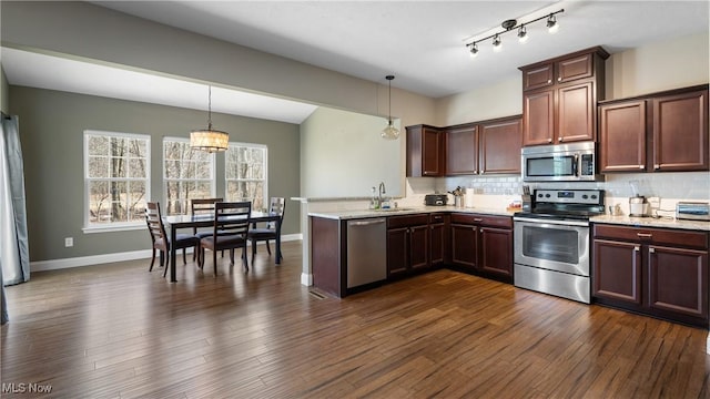 kitchen with hanging light fixtures, backsplash, stainless steel appliances, and dark wood-style flooring