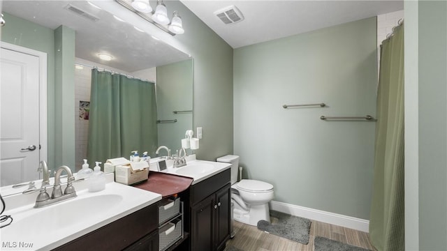 bathroom featuring baseboards, wood finished floors, visible vents, and a sink