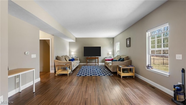 living room featuring visible vents, dark wood-style floors, baseboards, and a wealth of natural light