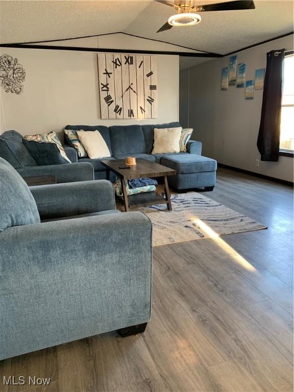 living area with wood finished floors, a ceiling fan, and vaulted ceiling