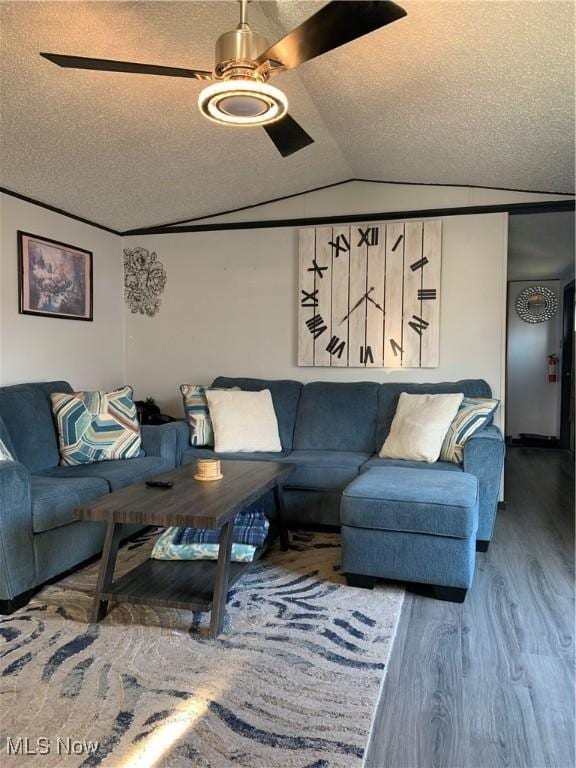 living area with ceiling fan, a textured ceiling, lofted ceiling, and wood finished floors