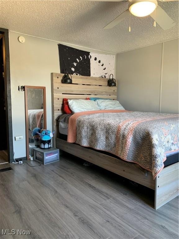 bedroom with a textured ceiling, a ceiling fan, and wood finished floors