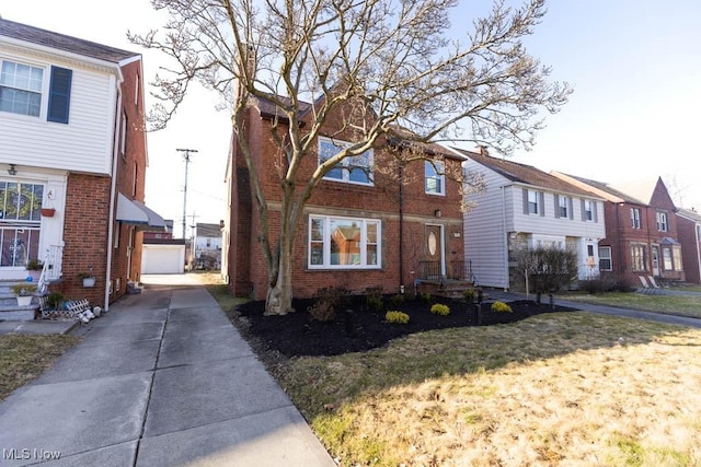 view of front of property with an outdoor structure, brick siding, and a front yard