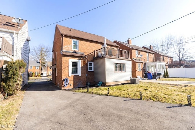 view of front of home featuring a residential view, brick siding, central AC unit, and fence