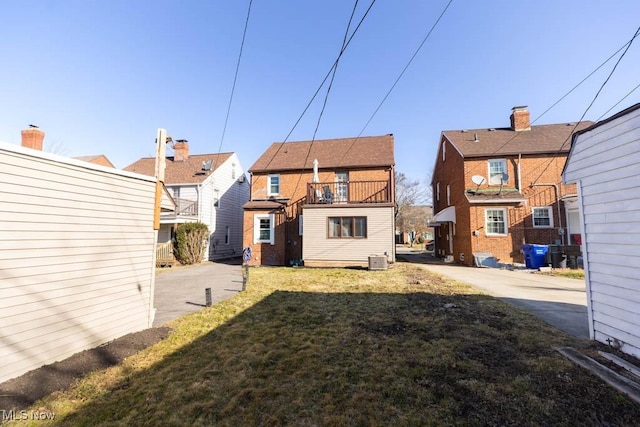 rear view of house featuring central AC unit and a yard