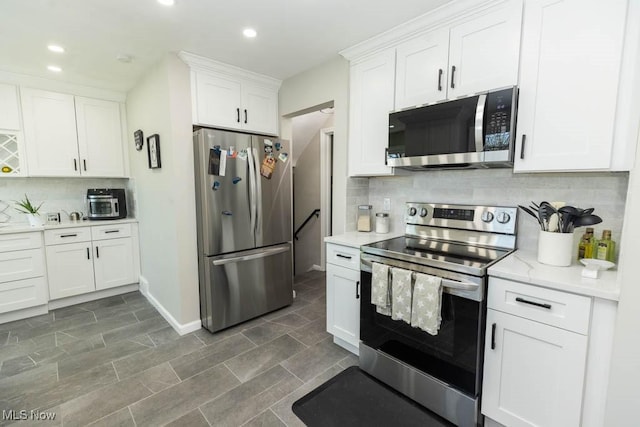 kitchen with recessed lighting, backsplash, appliances with stainless steel finishes, and white cabinetry