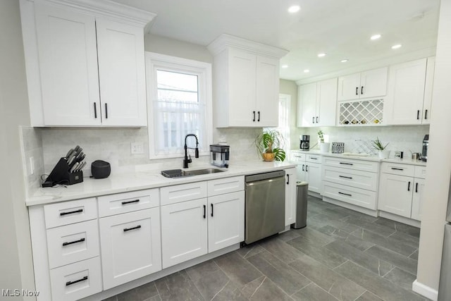 kitchen featuring stainless steel dishwasher, white cabinets, a wealth of natural light, and a sink