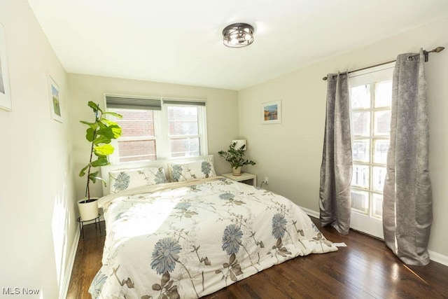 bedroom with dark wood finished floors and baseboards