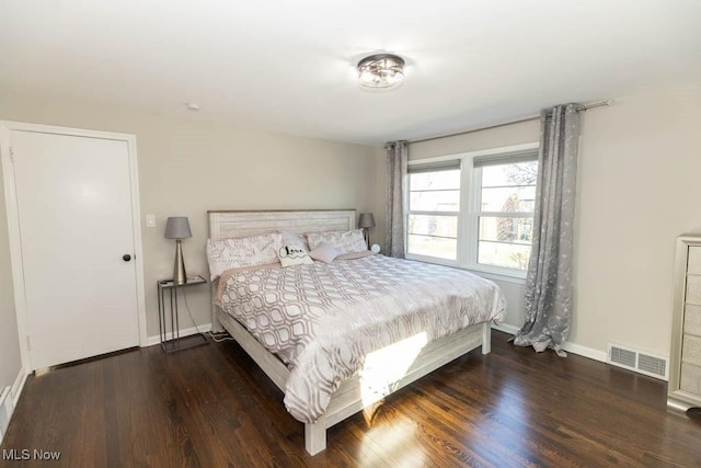 bedroom with visible vents, baseboards, and wood finished floors