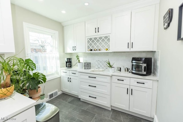 kitchen featuring tasteful backsplash, white cabinets, and light countertops