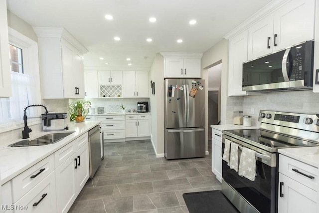 kitchen with a sink, decorative backsplash, white cabinetry, and stainless steel appliances