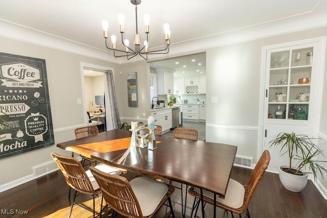 dining space featuring a chandelier, visible vents, baseboards, and wood finished floors