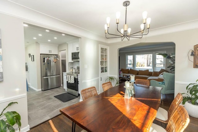 dining room with ornamental molding, recessed lighting, arched walkways, an inviting chandelier, and light wood finished floors