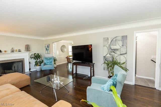 living room featuring arched walkways, a fireplace, baseboards, and wood finished floors