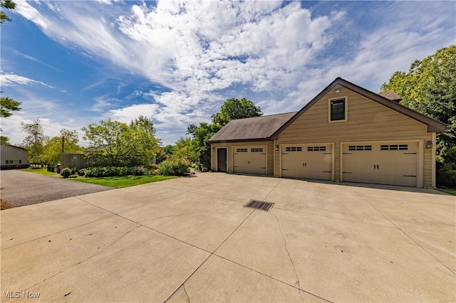 view of side of property featuring a garage, an outdoor structure, and driveway