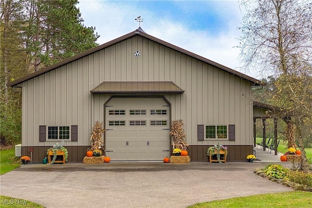 view of front of house featuring a standing seam roof, central AC, an outdoor structure, a garage, and metal roof