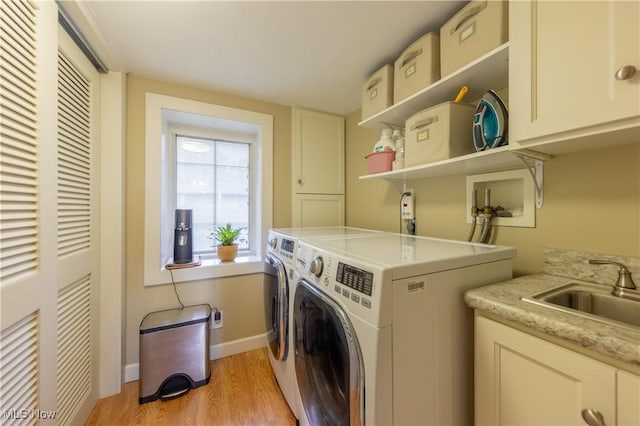 laundry room featuring baseboards, washing machine and dryer, light wood-type flooring, cabinet space, and a sink