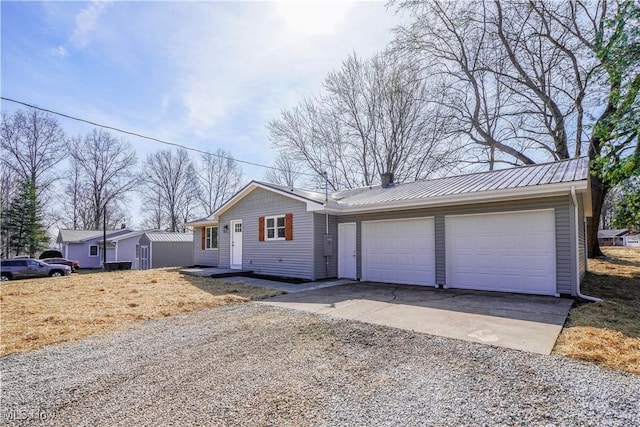 view of front of property featuring an attached garage, metal roof, and gravel driveway