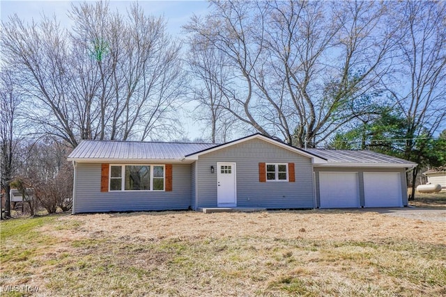 ranch-style home with a garage, a front yard, metal roof, and driveway