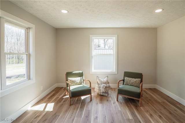 living area with light wood-style flooring, recessed lighting, baseboards, and a textured ceiling