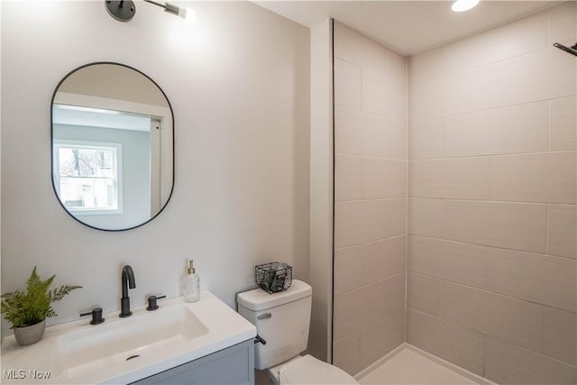 bathroom featuring vanity, toilet, and tiled shower